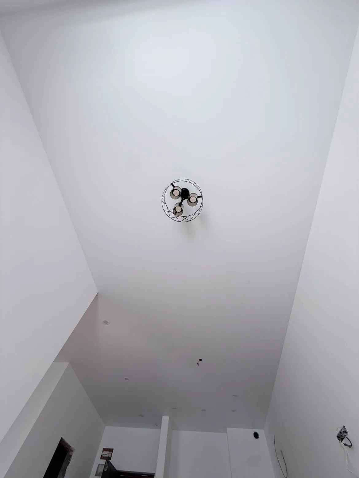 The same room with a white stretch ceiling and a chandelier, after installation
