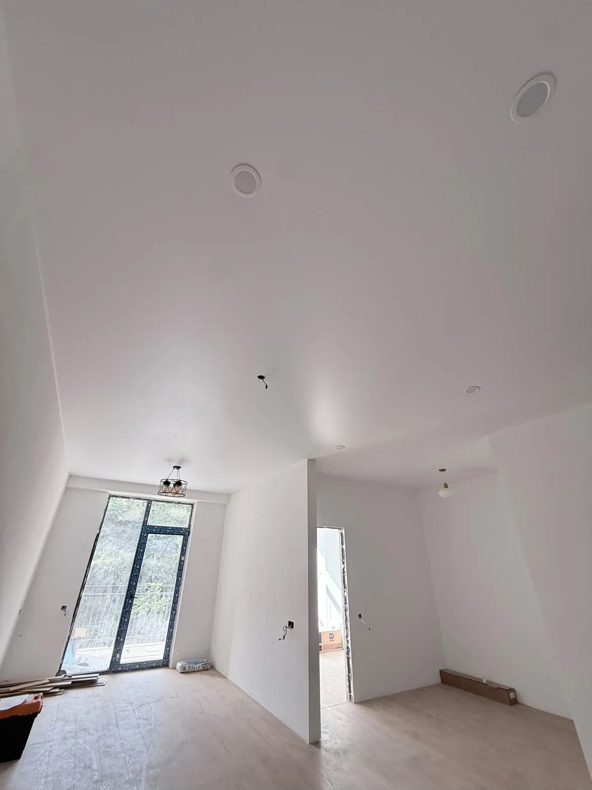 White stretch ceiling with spotlights by the balcony door, after installation